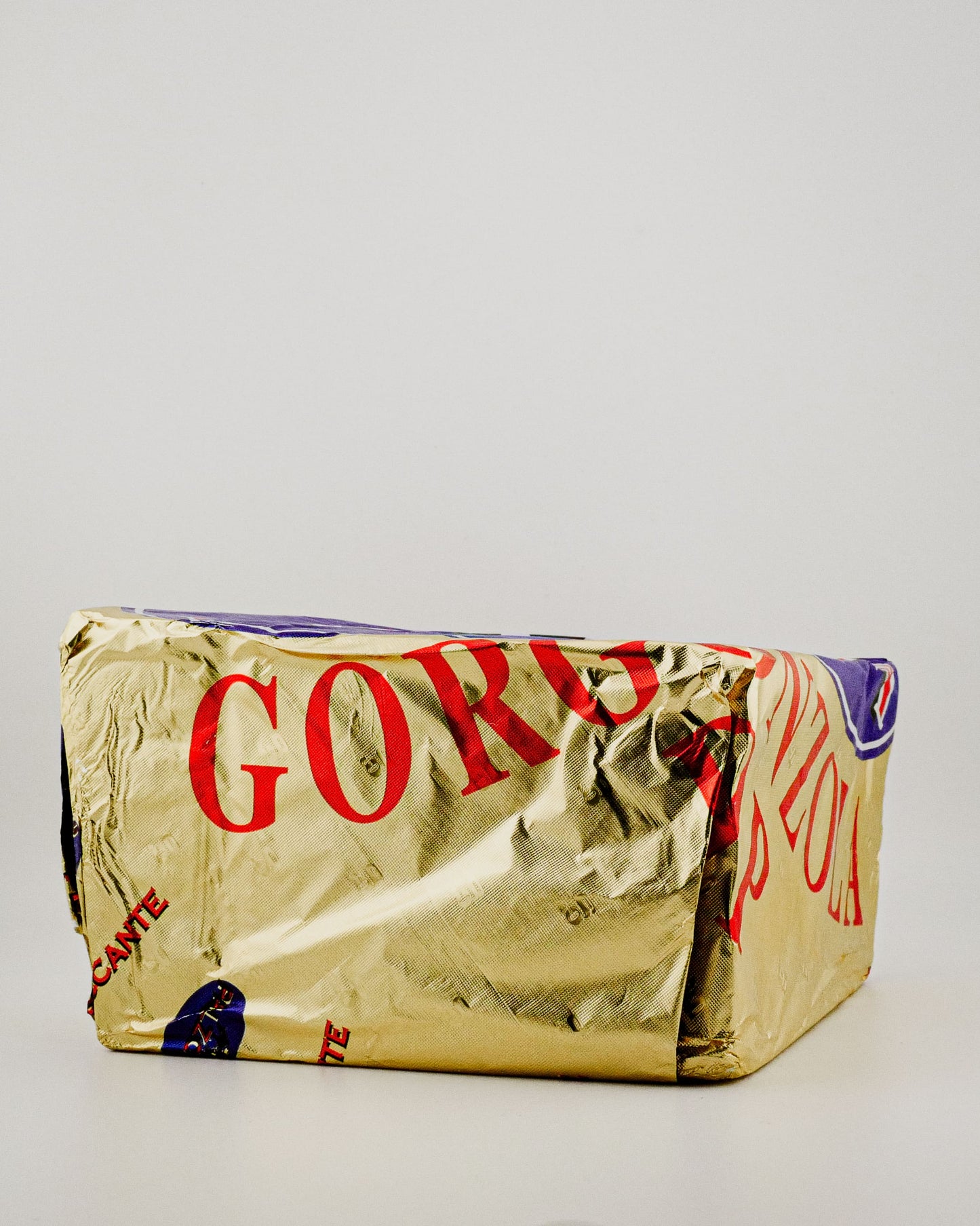 Gold-wrapped product with visible branding on a light gray background