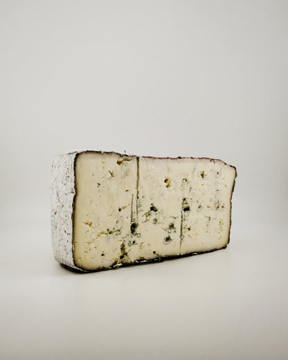 Block of blue cheese that is soaked in red wine on a light gray background