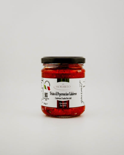 Jar of red pepper spread with a label on a white background
