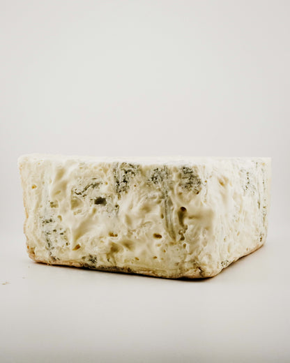 Block of creamy blue cheese on a light gray background