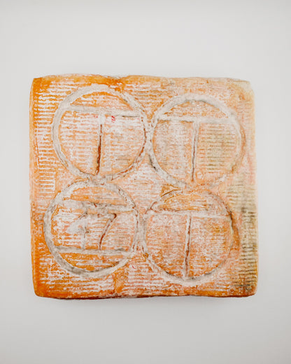 Square piece of soap with circular grooves on a light gray background