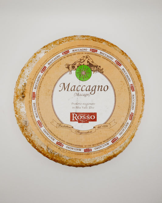 Round Maccagno cheese with a label on a light gray background