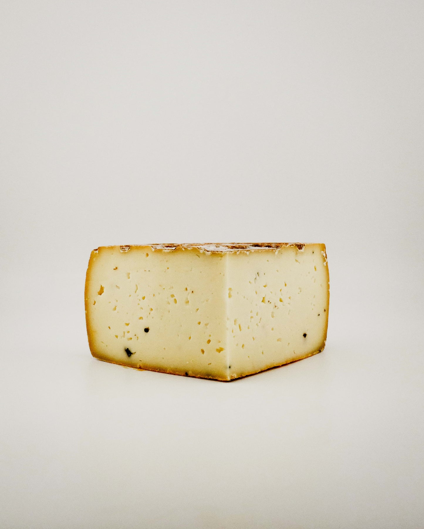 Block of Tomatoes Truffle cheese on a light gray background