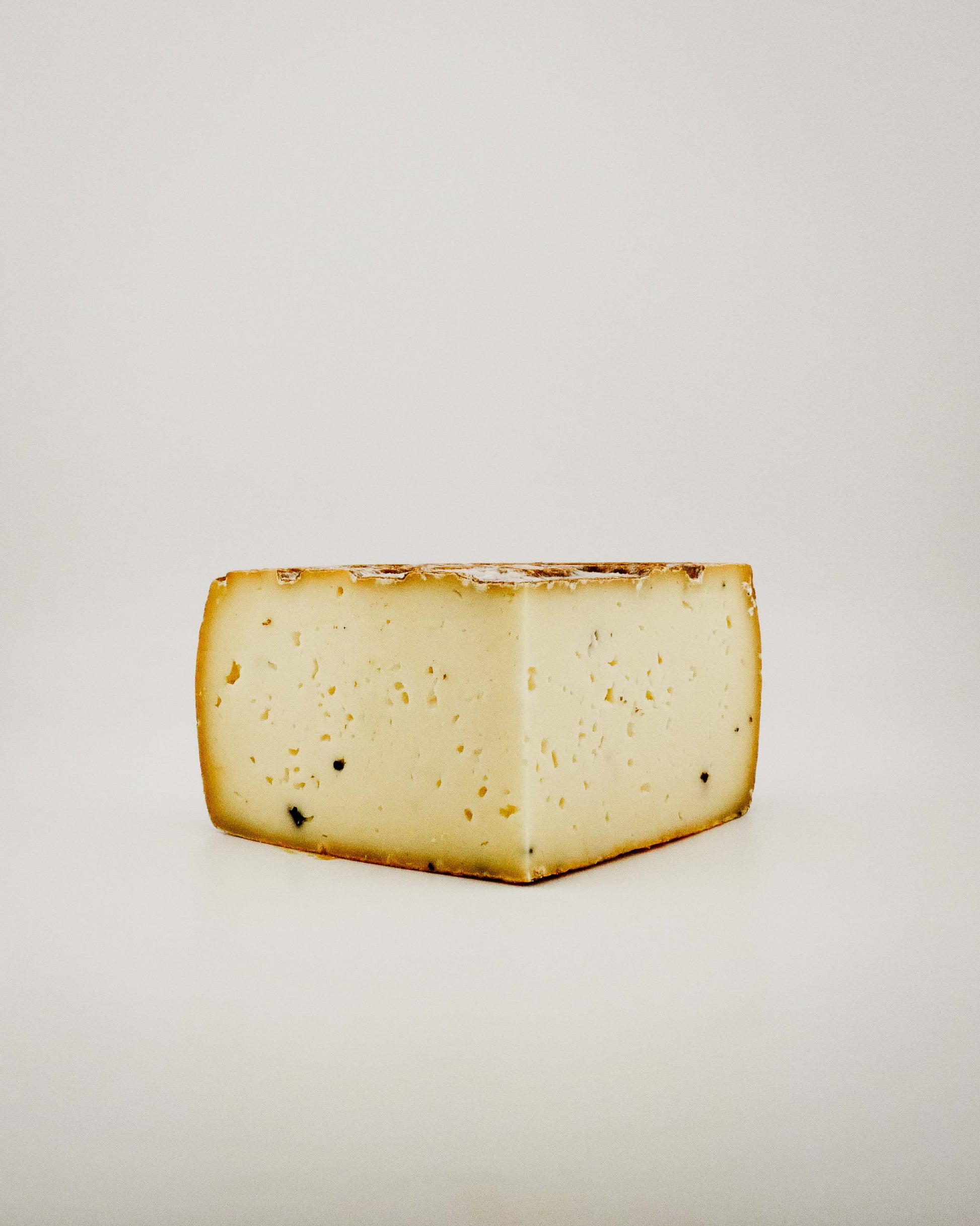 Block of Tomatoes Truffle cheese on a light gray background